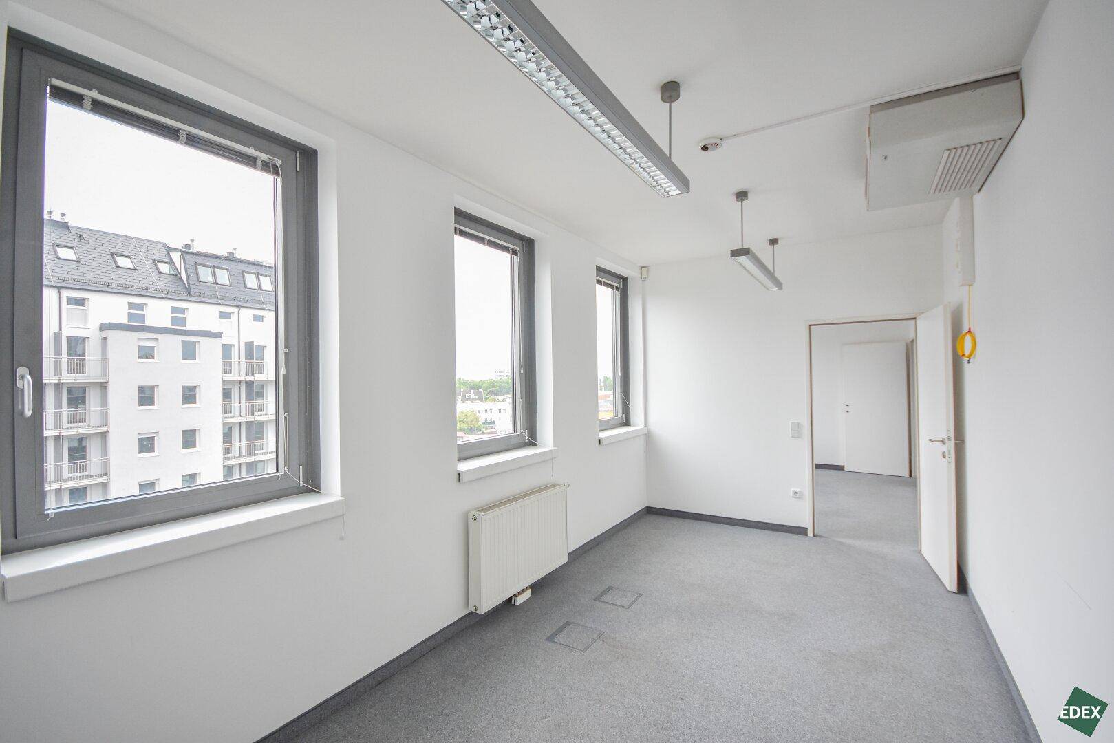 Büro mit Teppichboden, großen Fenstern und Klimaanlage an der Decke, sorgt für angenehmes Klima.