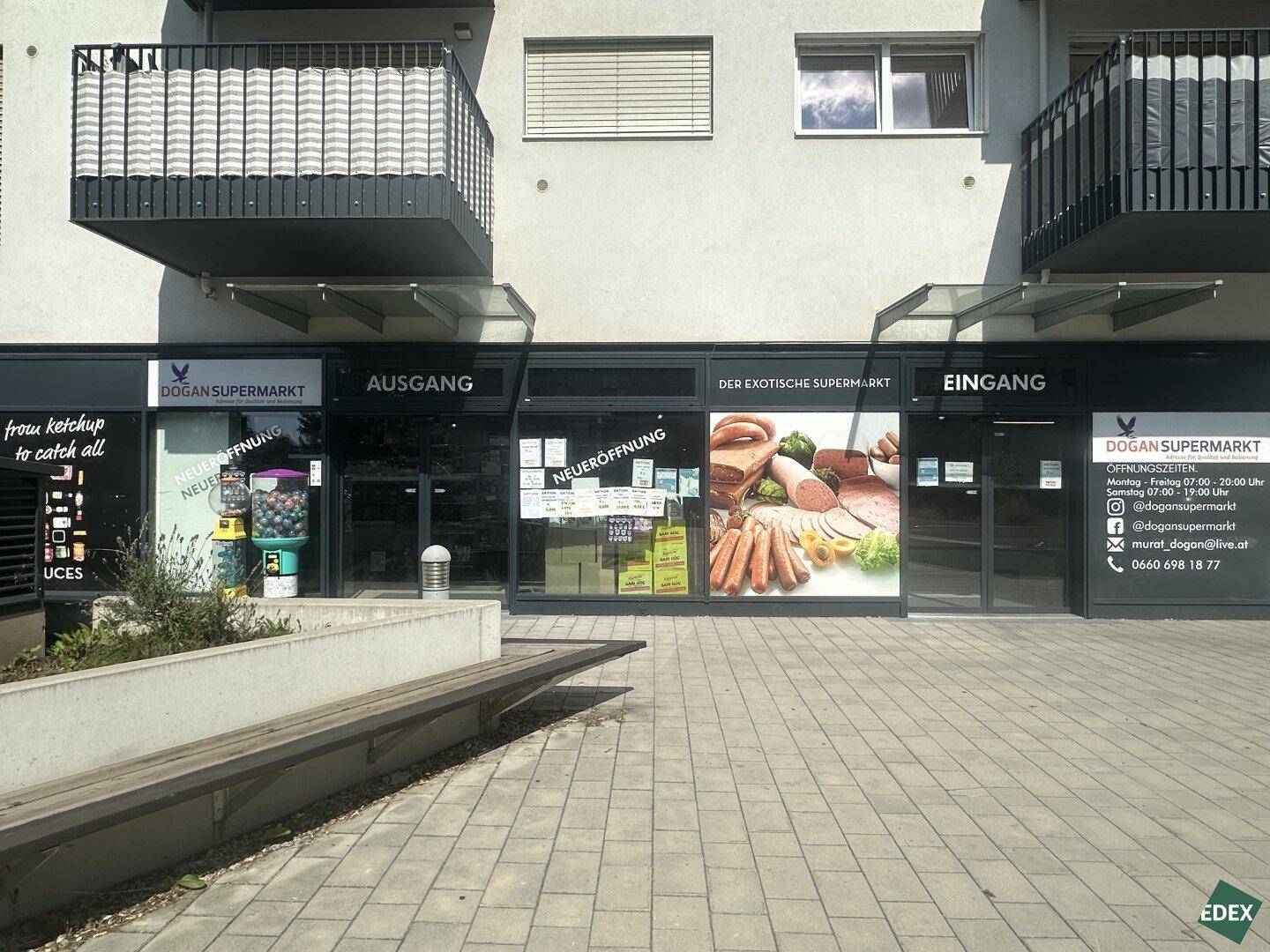 Nahaufnahme der Ladenfronten mit Eingangs- und Ausgangsschildern sowie Produktwerbung des Supermarktes.