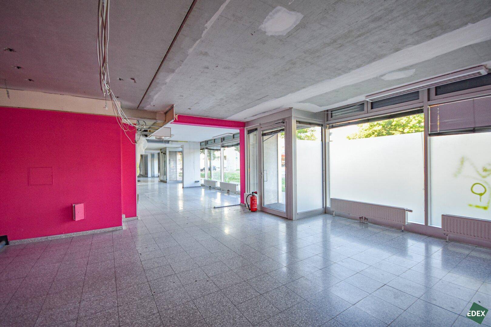 Weitläufiger Gewerberaum mit rosa Wänden, Fliesenboden und großen Fenstern, die viel Licht spenden.