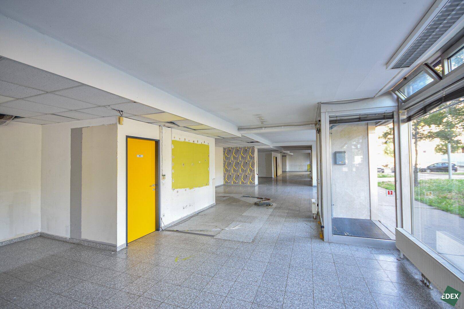 Gewerberaum mit gelber Tür und Wandpaneel, ergänzt durch eine gemusterte Akzentwand im Hintergrund.