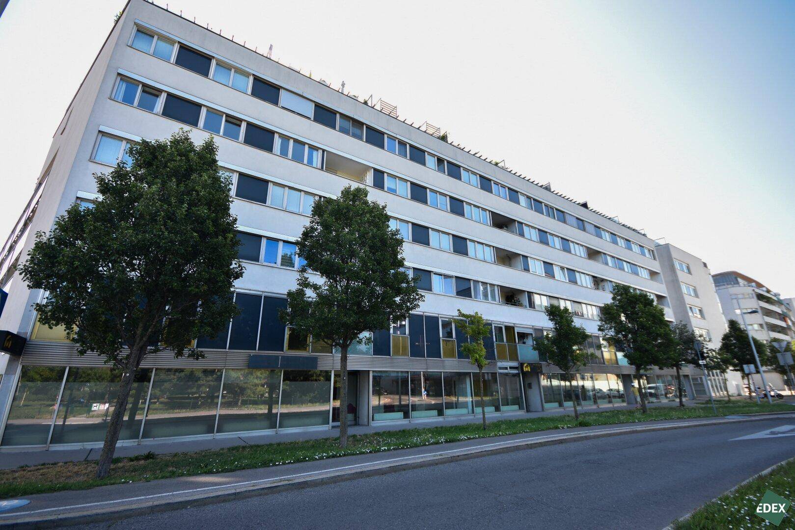 Weitwinkelaufnahme des modernen Mehrfamilienhauses mit zahlreichen Fenstern und Balkonen.