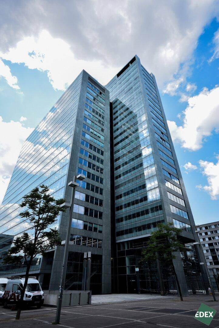 Modernes Hochhaus mit beeindruckender Glasfassade und vielen Fenstern unter einem bewölkten Himmel.