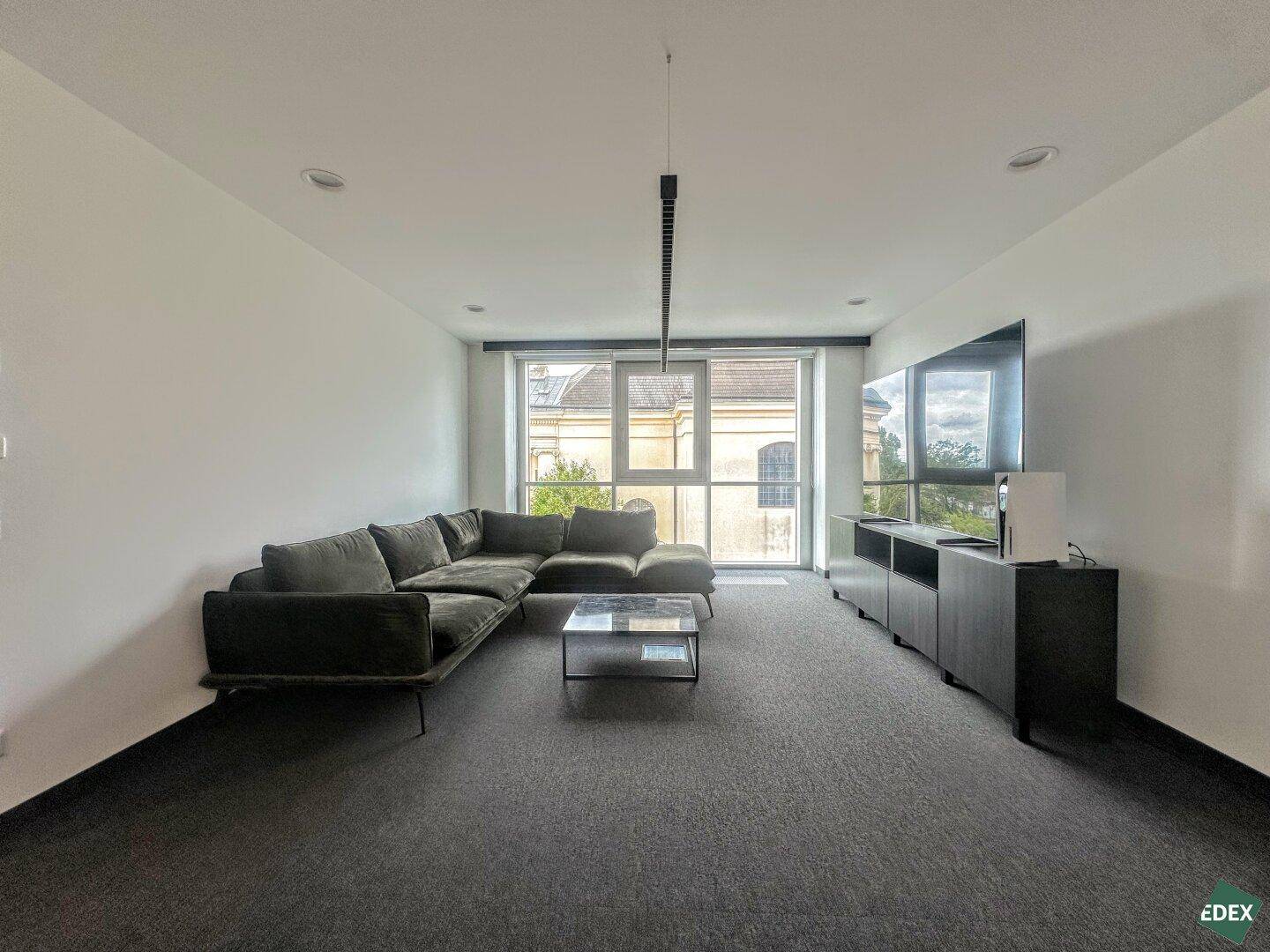 Moderner Loungebereich mit großem Ecksofa, Flachbildfernseher und stilvoller Medienkonsole.
