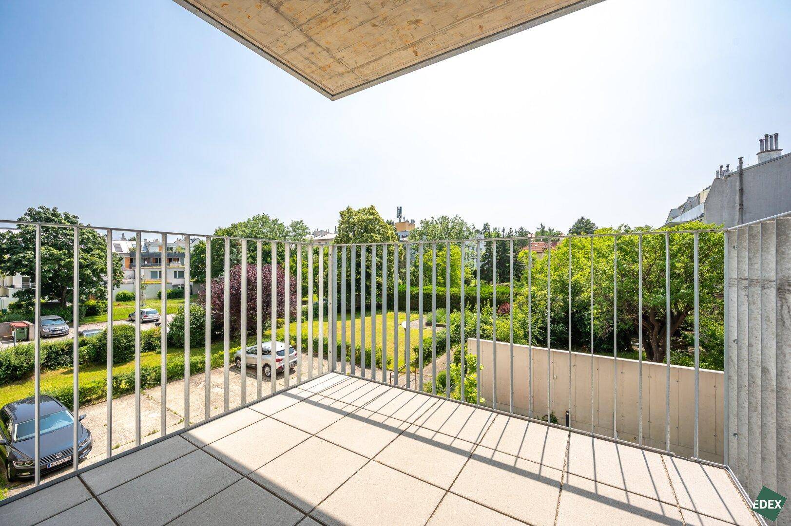 Großer Balkon mit Fliesenboden und weitem Blick auf die grüne Umgebung.