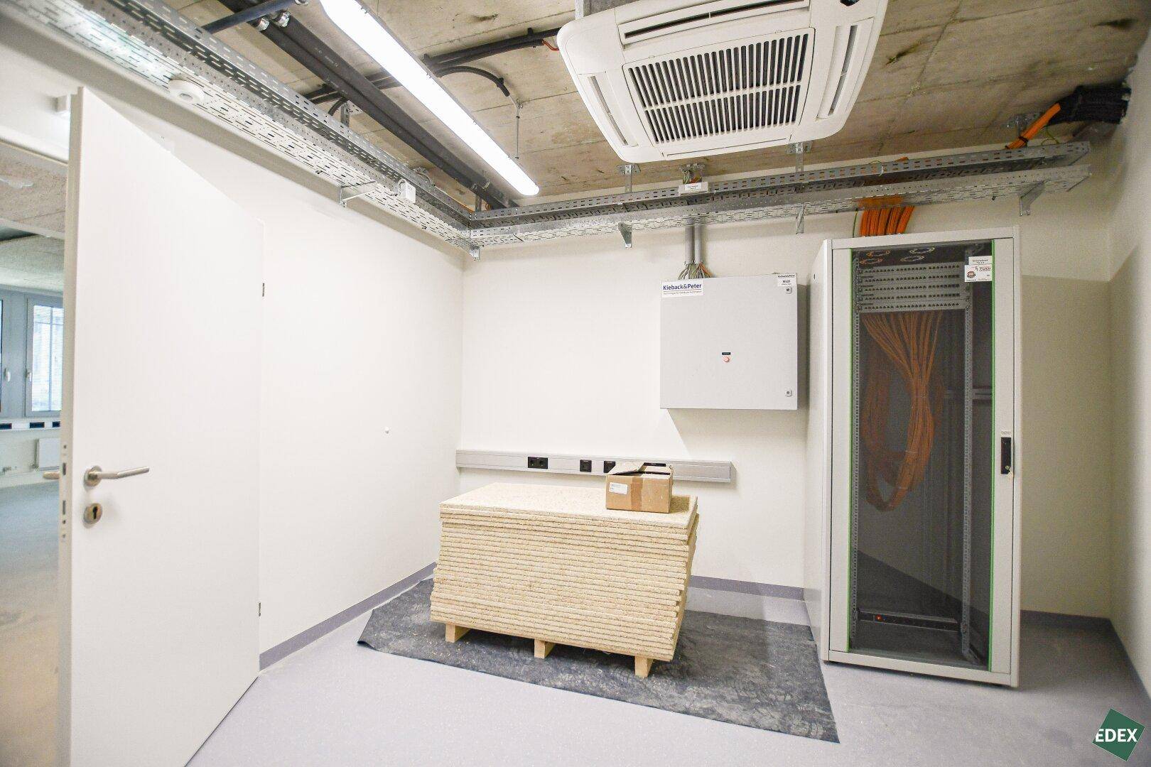 Serverraum mit Klimaanlage, Kabeltrassen und einem Serverschrank, bereit für die Technik.