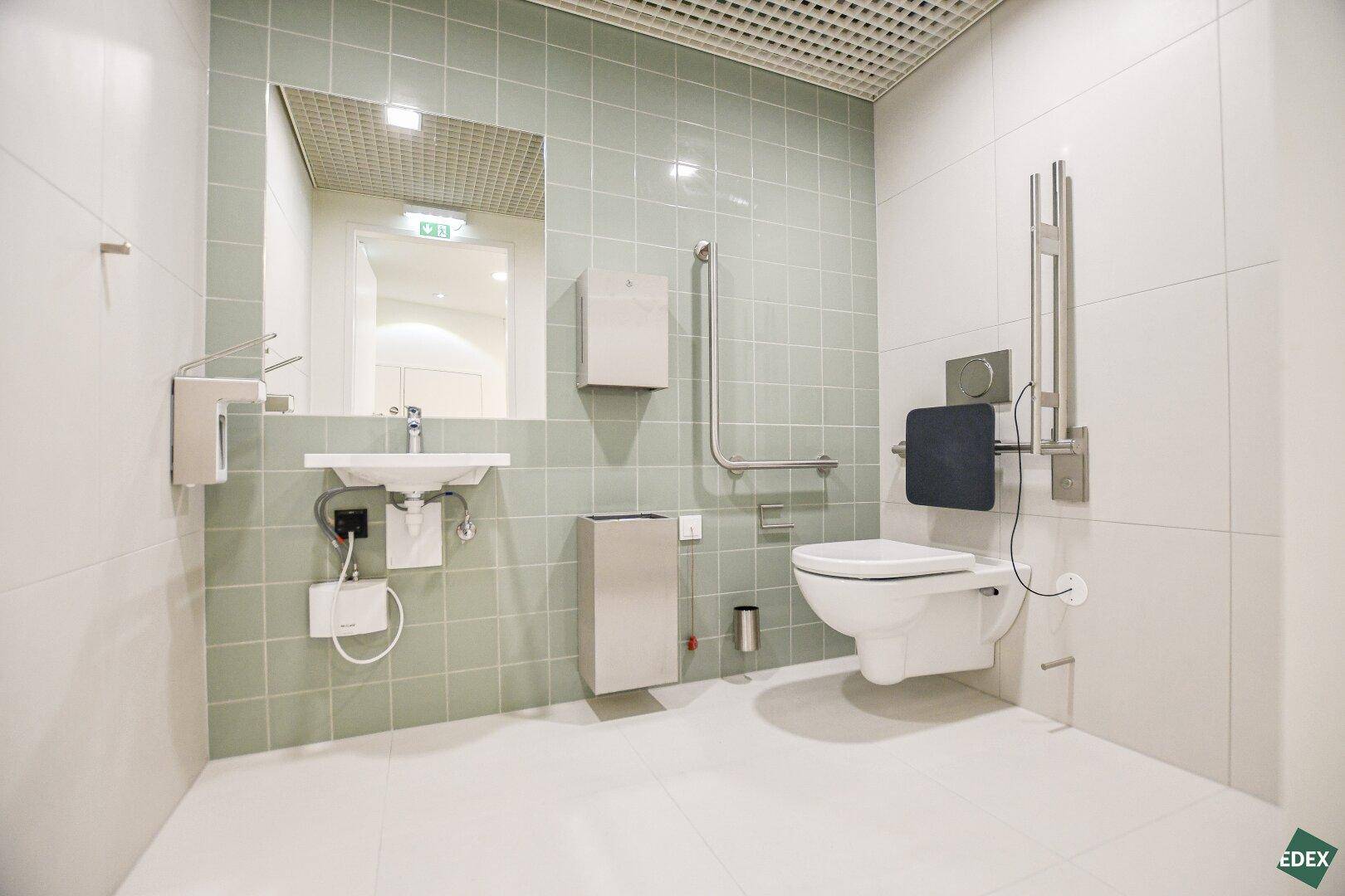 Barrierefreies Badezimmer mit Haltegriffen, unterfahrbarem Waschbecken und Wand-WC.