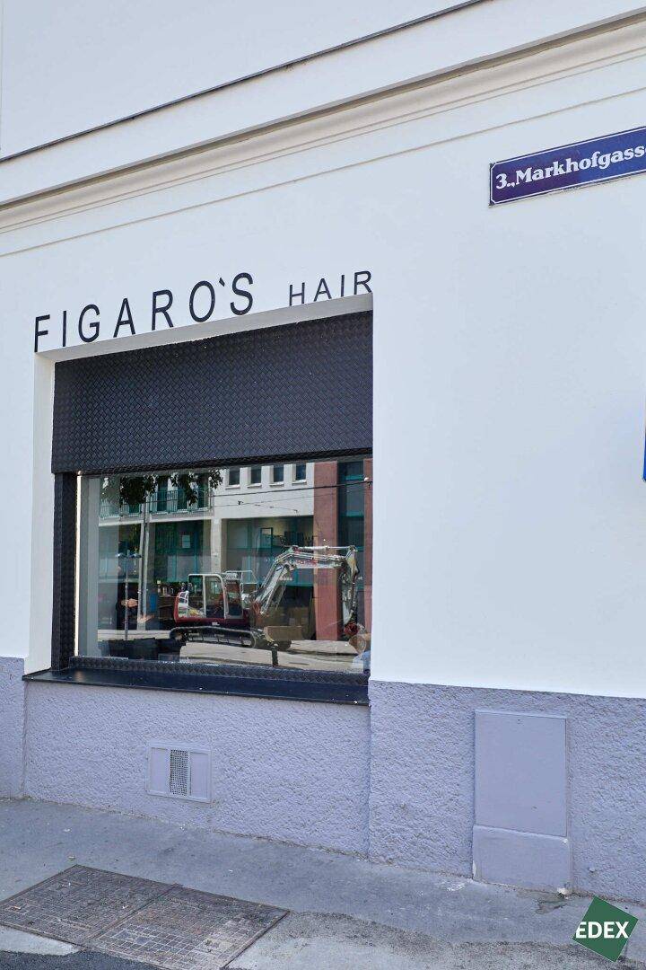 Außenansicht des Geschäftsfensters mit Rollladen und einem Straßenschild, das die Adresse anzeigt.