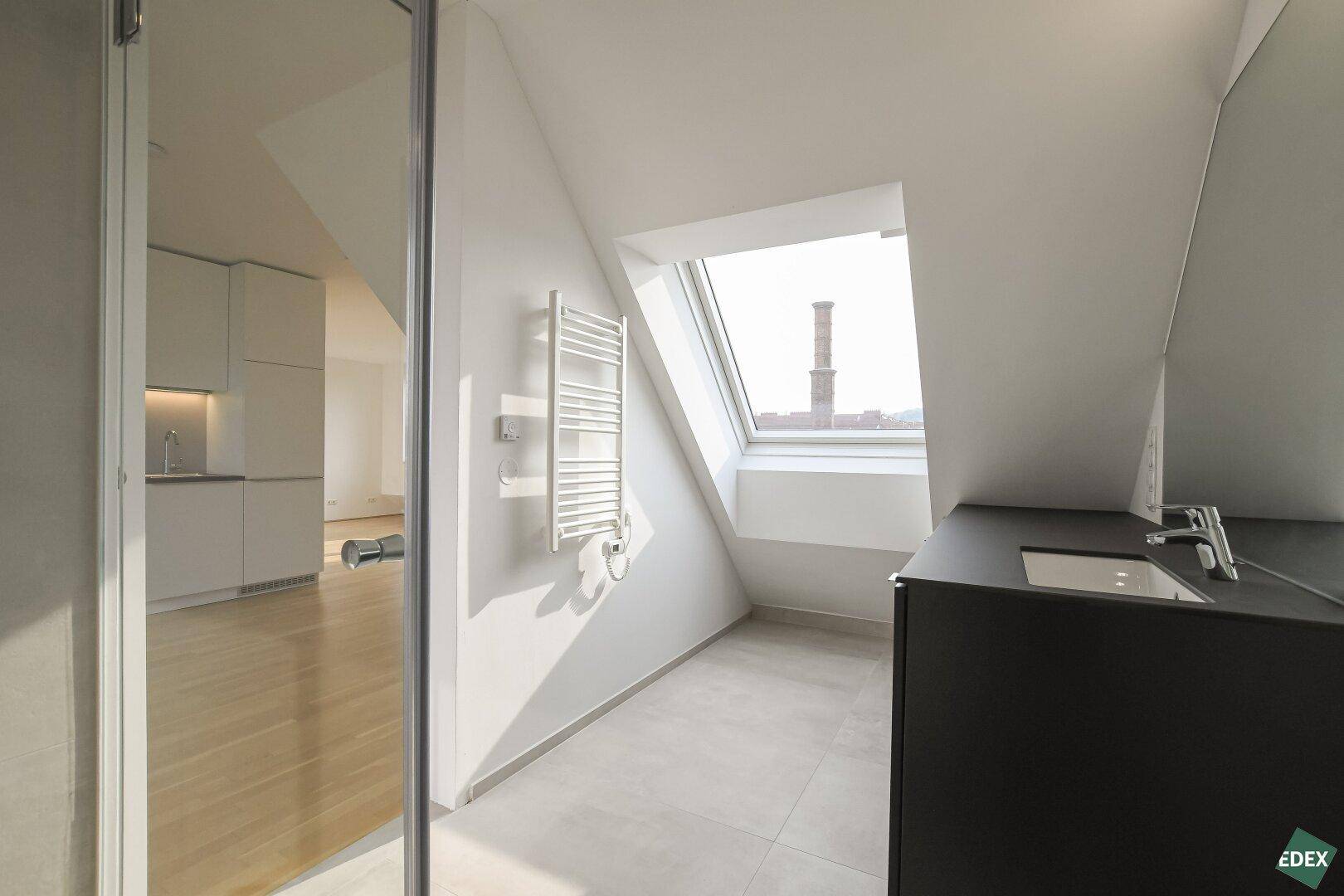 Modernes Badezimmer mit Dachschräge, Waschbecken und beheiztem Handtuchhalter.