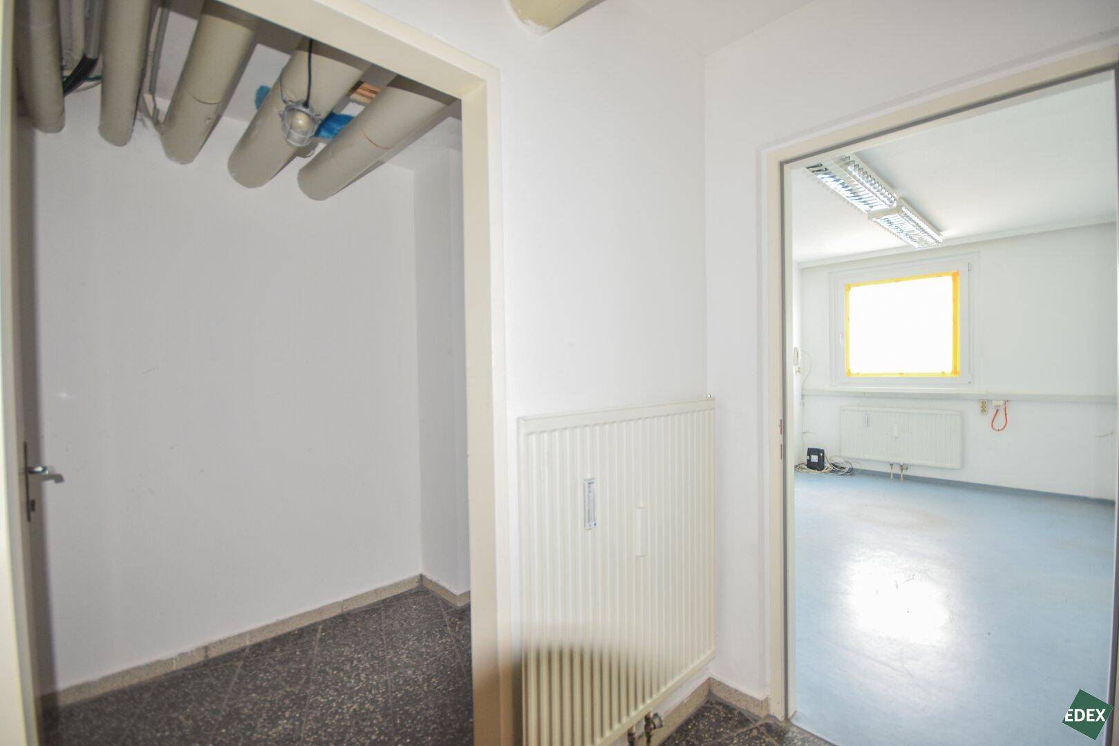 Abstellraum mit sichtbaren Rohren an der Decke und einem dunklen Terrazzoboden.