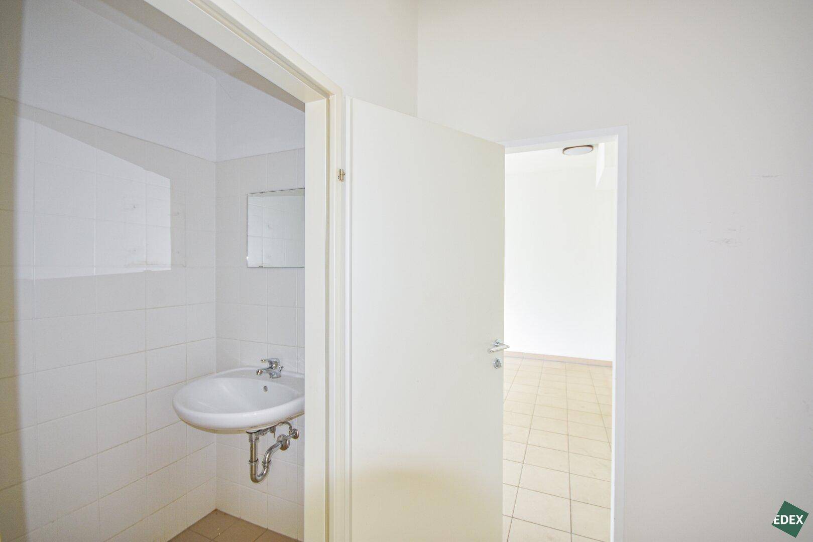 Kleines Badezimmer oder Gäste-WC mit Waschbecken und weißen Wandfliesen, funktional und hell.