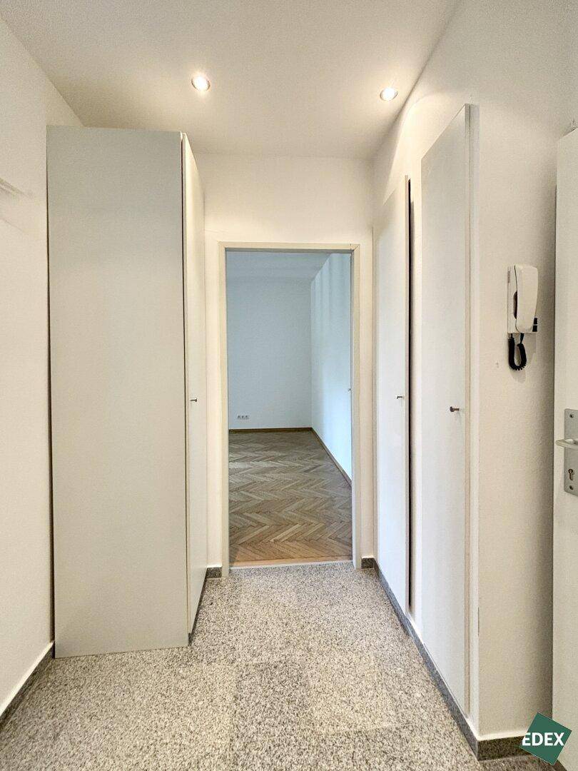 Heller Flur mit Einbauschränken und Terrazzoboden, der zu weiteren Räumen führt.