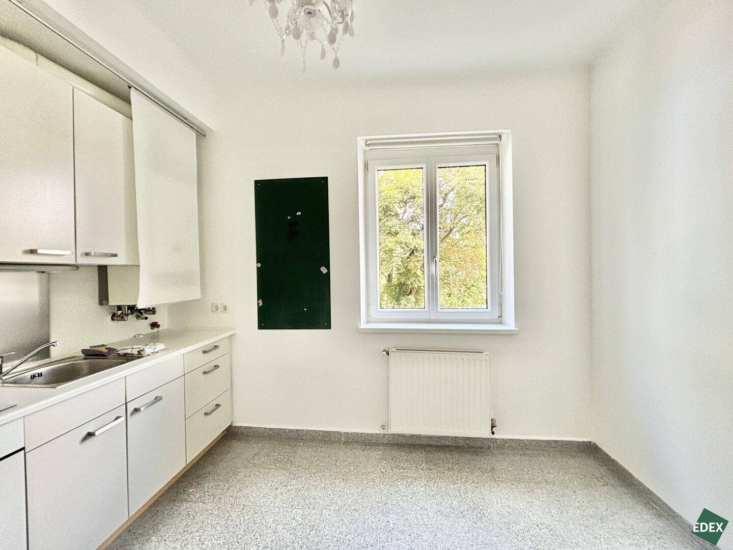 Helle Küchenzeile mit weißen Unterschränken und einem Fenster, das viel Tageslicht hereinlässt.