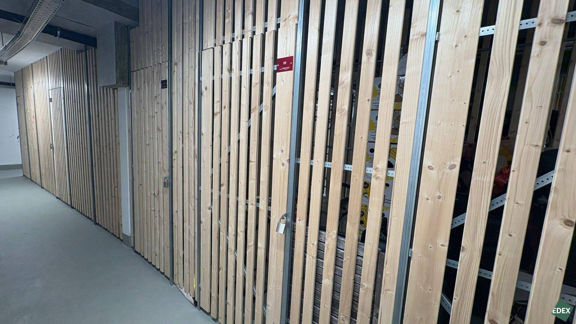 Kellerabteile mit Holzlattenwänden bieten zusätzlichen Stauraum für die Bewohner des Gebäudes.