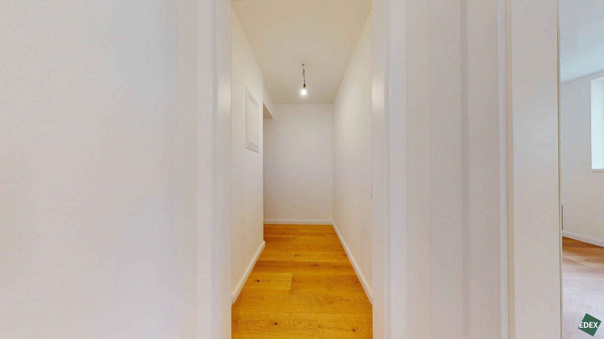 Heller Flur mit Holzparkettboden, der zu den privaten Räumen der Wohnung führt.