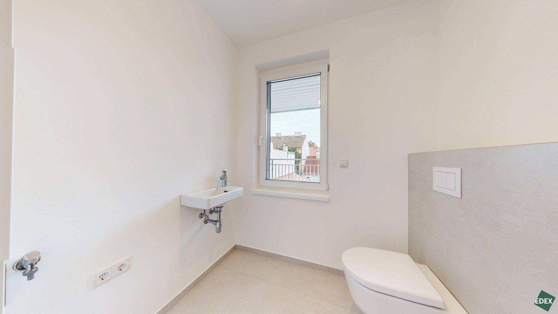 Modernes Gäste-WC mit wandhängender Toilette, kleinem Waschbecken und Fenster.