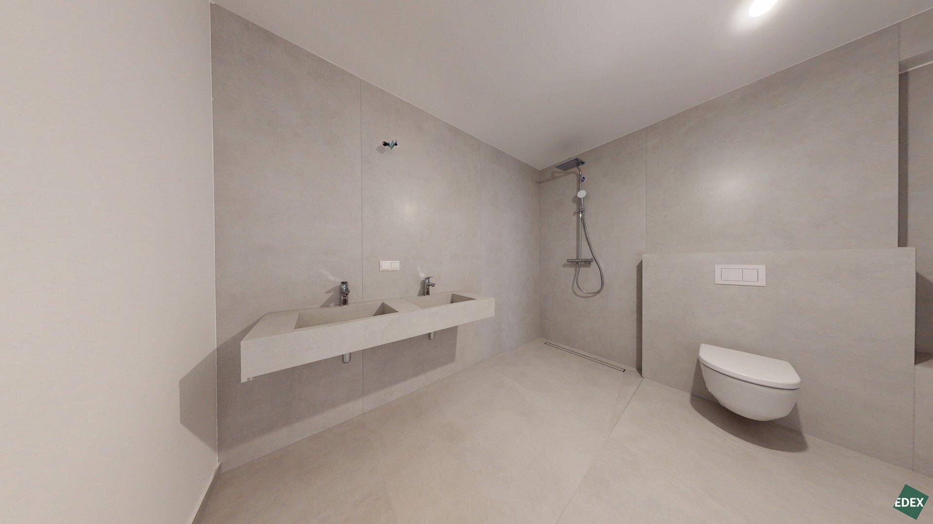 Elegantes Badezimmer mit Doppelwaschbecken, begehbarer Dusche und wandhängender Toilette.