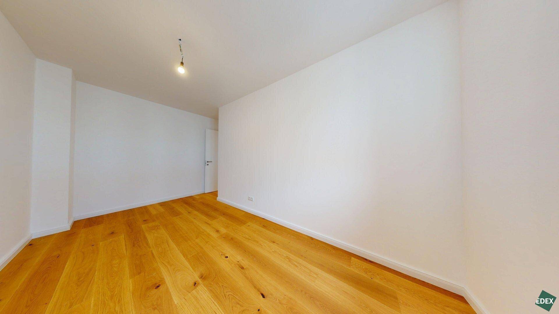 Geräumiges Zimmer mit Holzboden und weiß gestrichenen Wänden, bereit zur individuellen Einrichtung.
