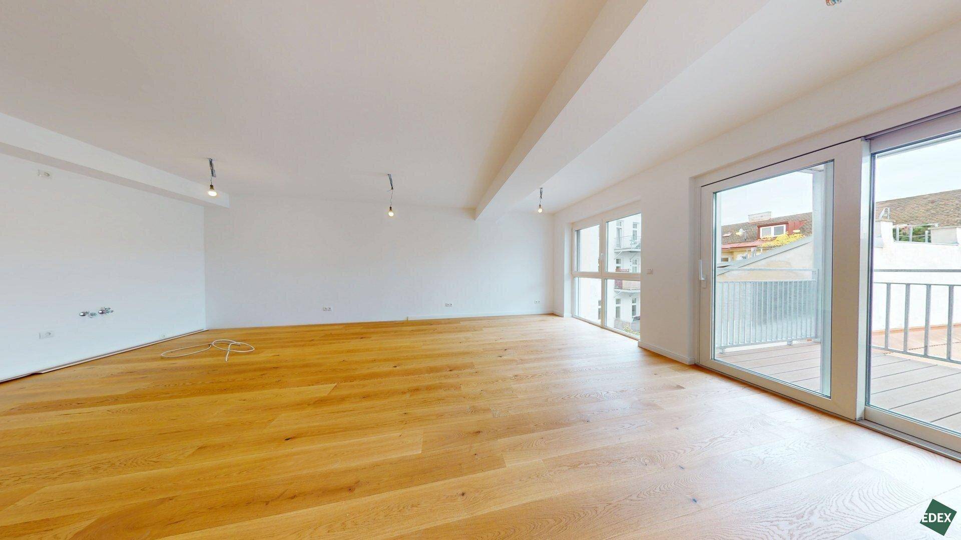 Helles, geräumiges Zimmer mit Holzboden und Zugang zu einem Balkon, ideal als Wohnbereich.