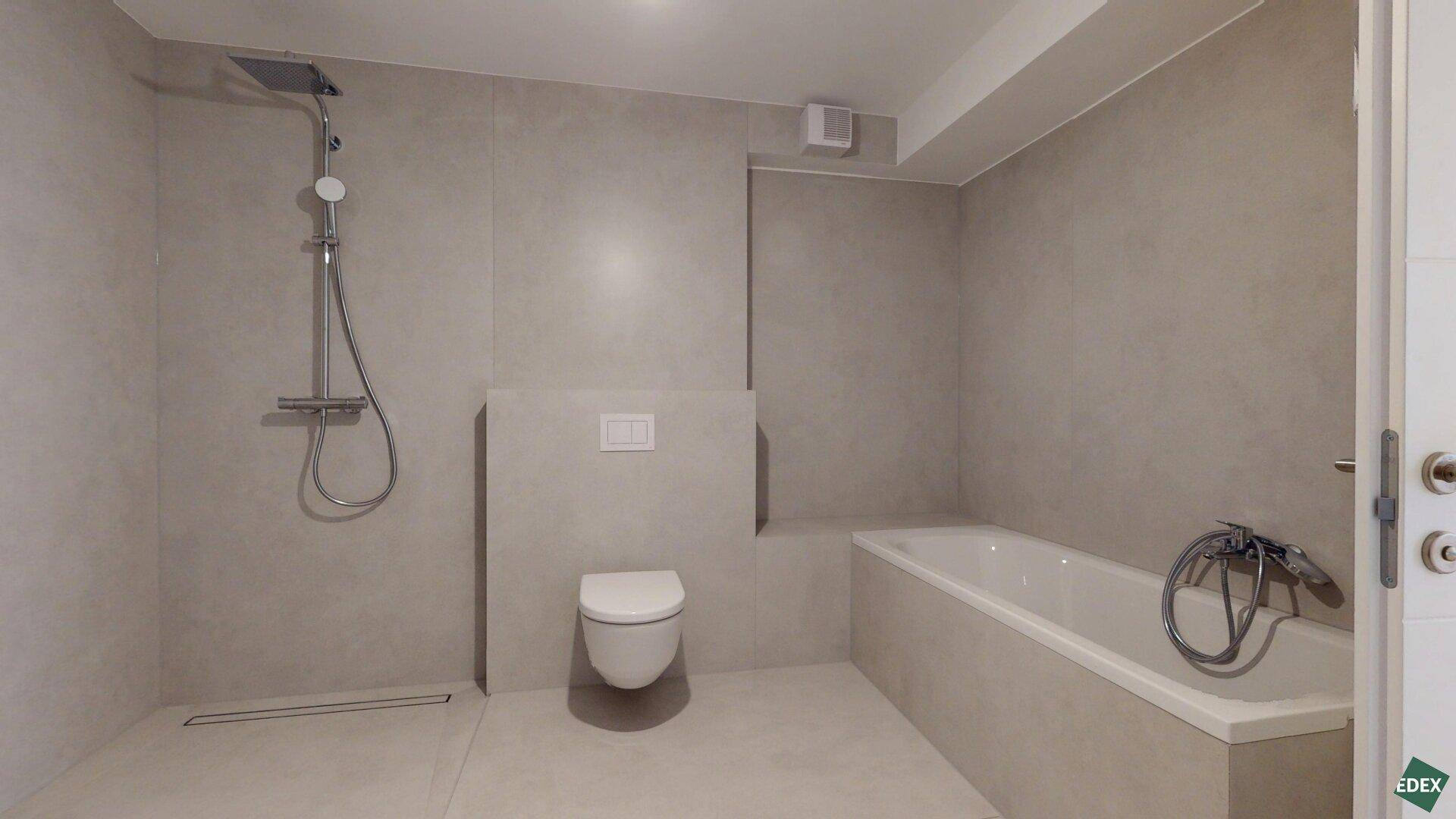 Modernes Badezimmer mit Badewanne, Dusche und wandhängendem WC in neutralen Farbtönen.
