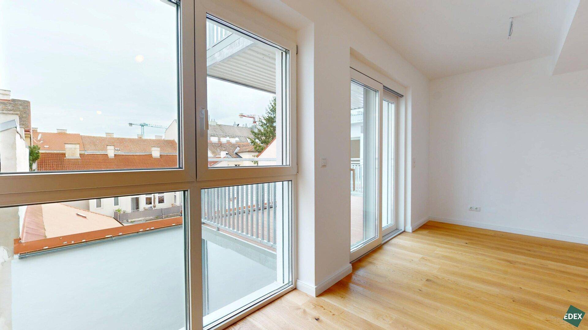 Blick aus dem Wohnzimmer auf den Balkon mit Stadtansicht und viel Tageslicht.
