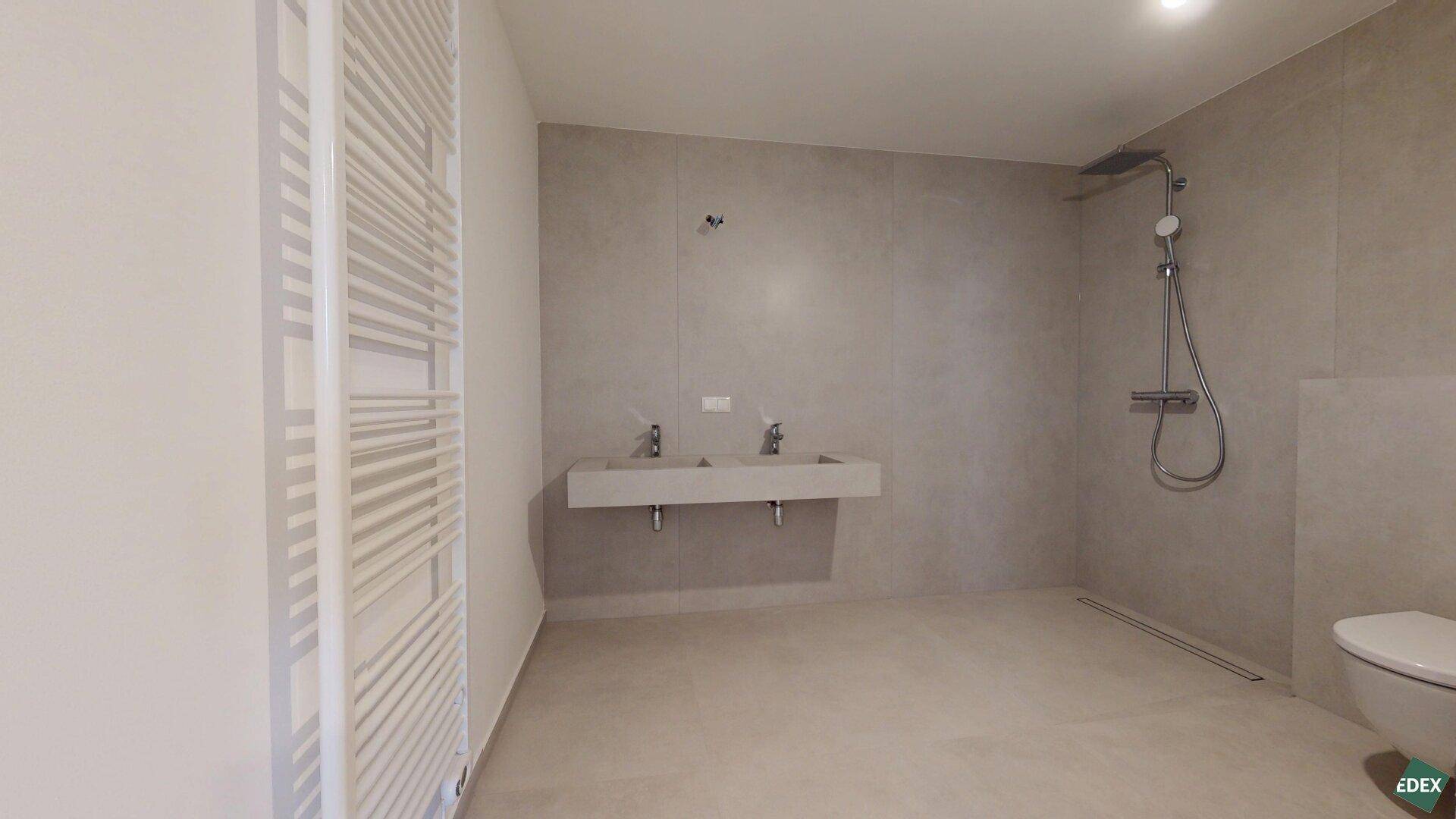 Modernes Badezimmer mit Doppelwaschbecken, großer begehbarer Dusche und Handtuchheizkörper.