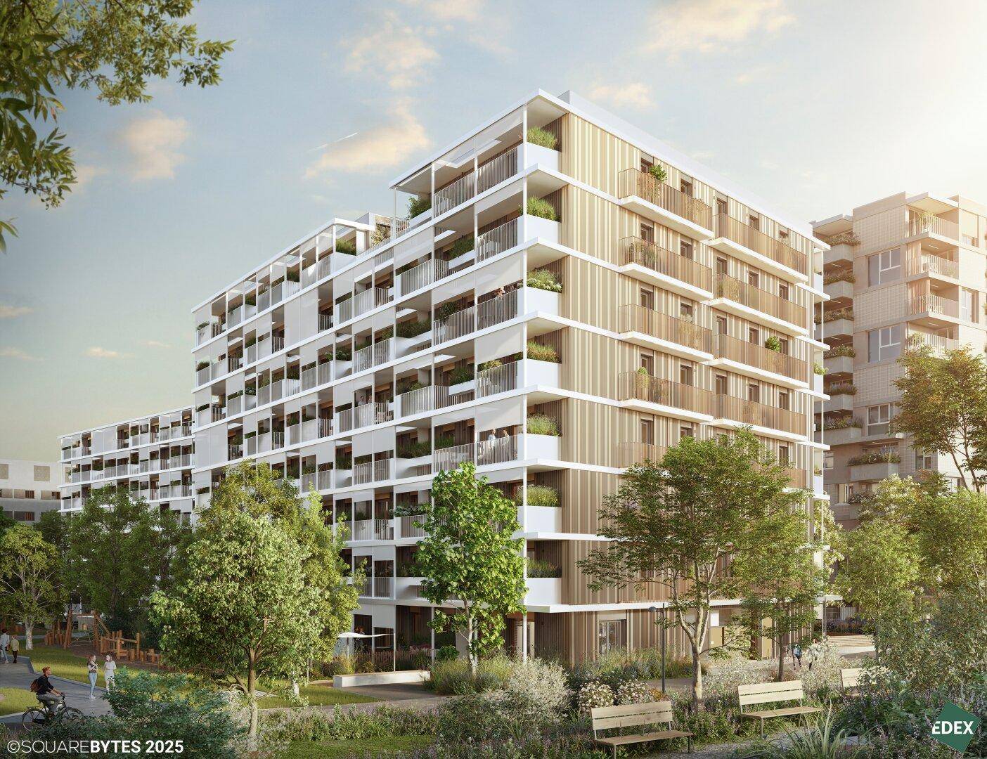 Moderne Wohnanlage mit mehreren Gebäuden, Balkonen und begrünten Außenbereichen unter blauem Himmel.