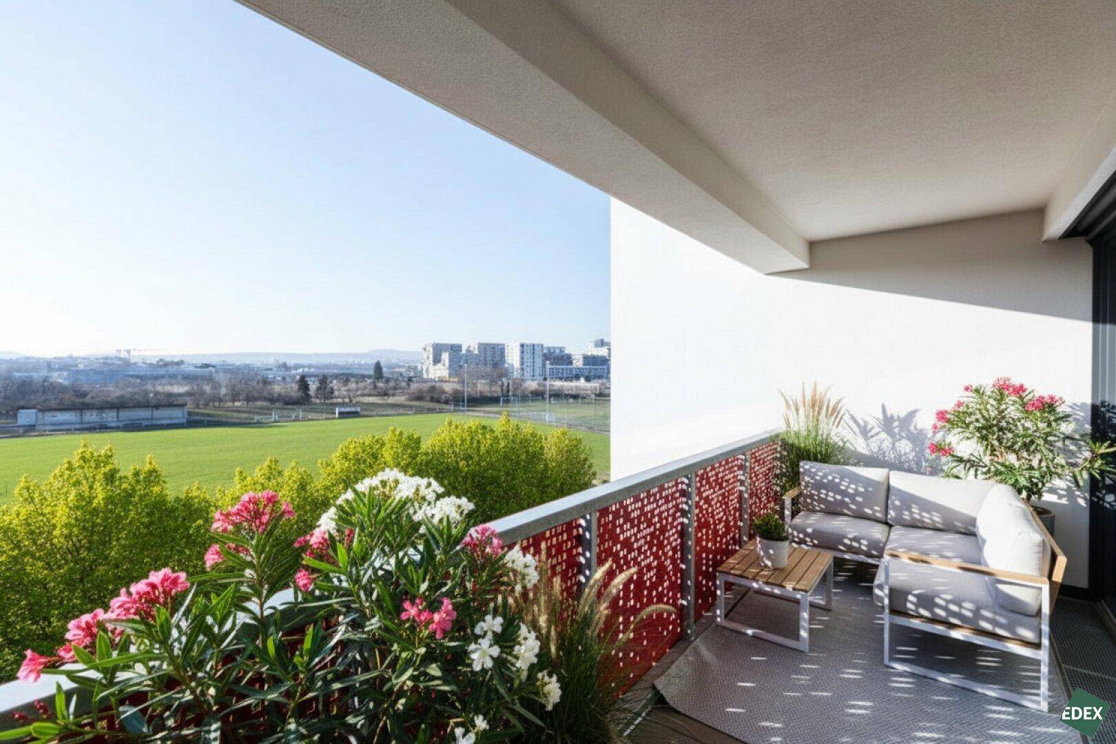 Geräumiger Balkon mit Sitzgelegenheiten, Pflanzen und weitem Blick ins Grüne und auf die Stadt.