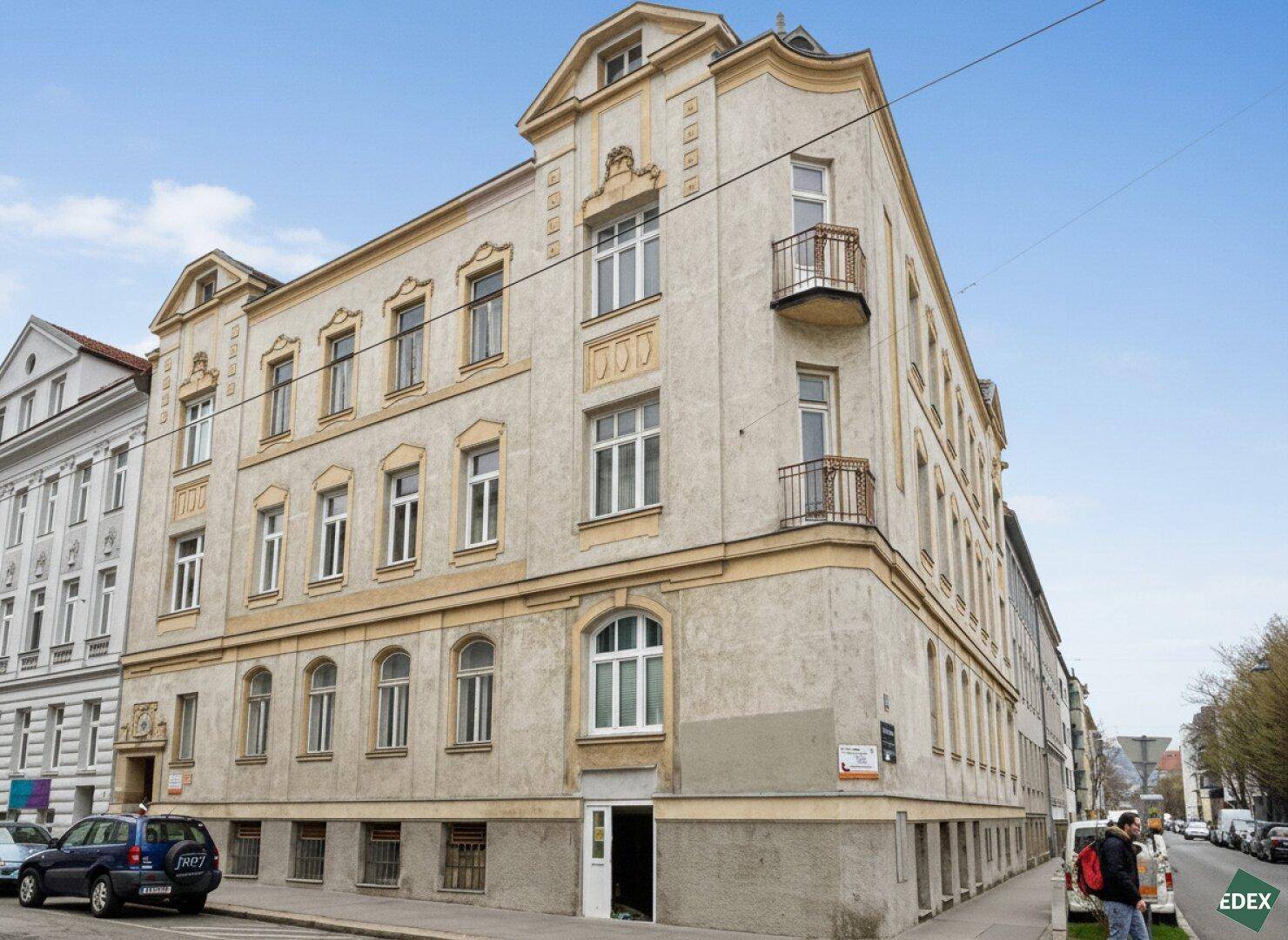 Eckgebäude eines historischen Mehrfamilienhauses mit Balkonen und Straßenansicht.