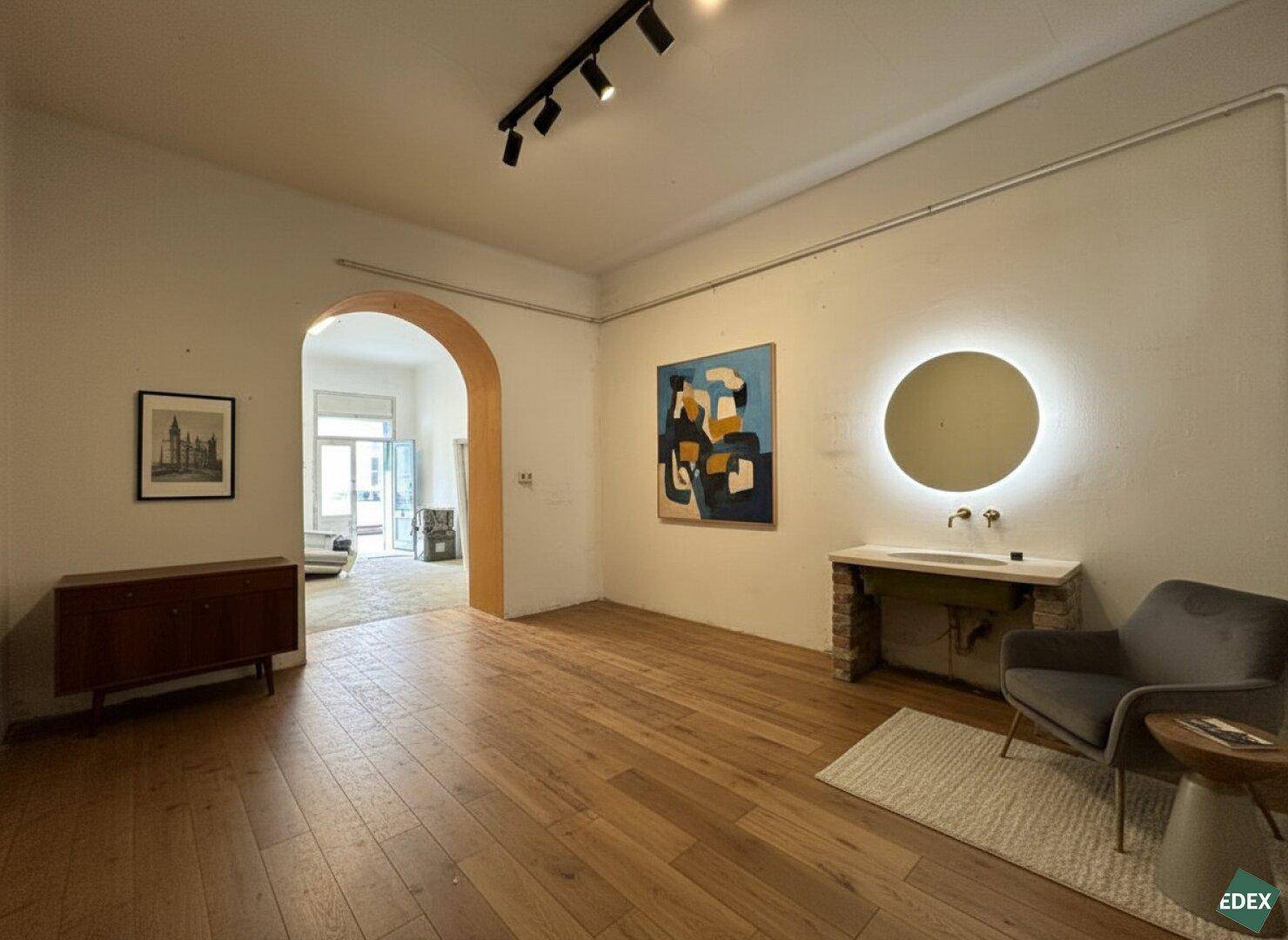 Heller Raum mit Holzboden, modernem Waschbecken und Kunstwerken an den Wänden.
