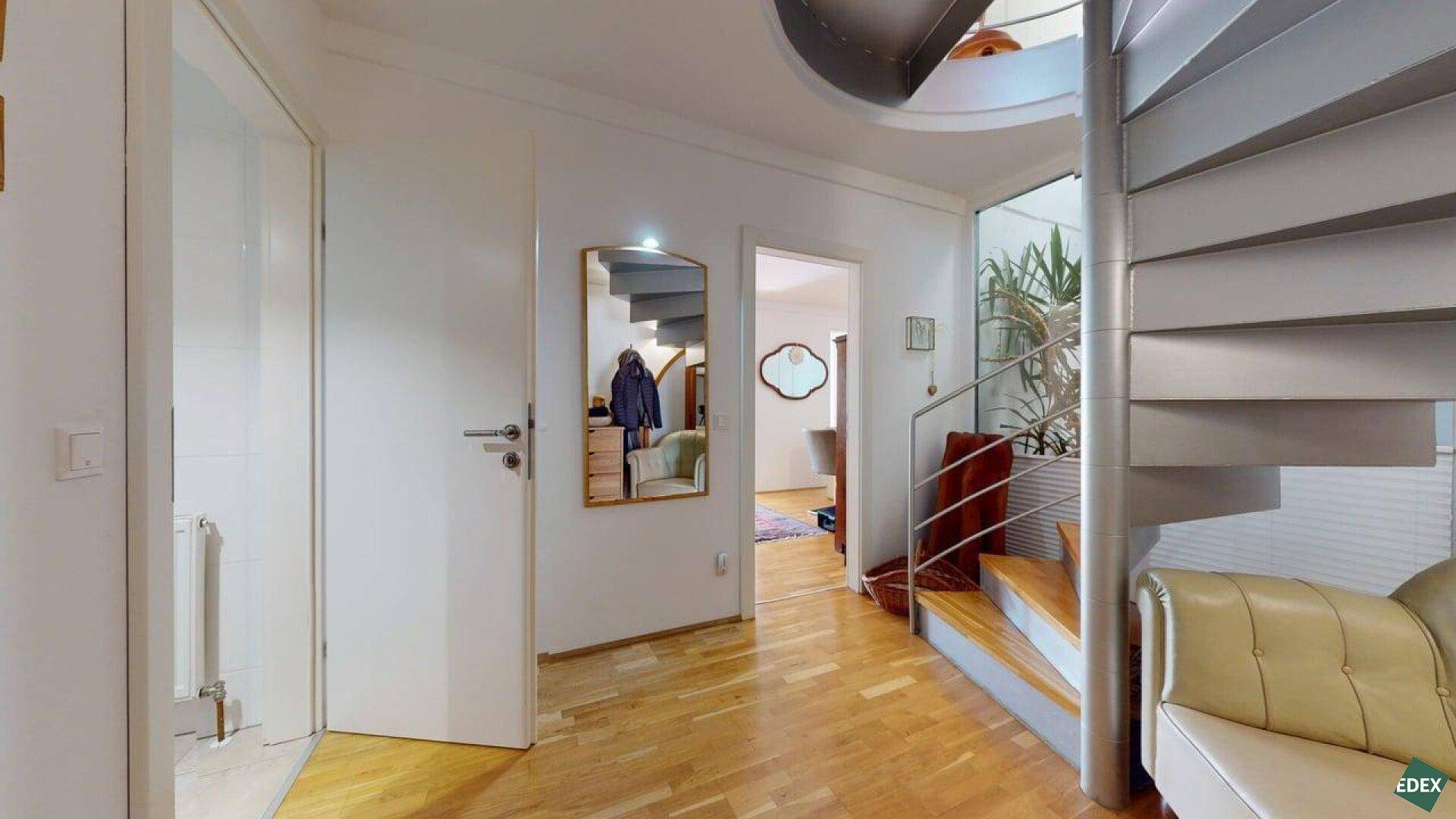 Heller Eingangsbereich mit Spiegel, Holzboden und eleganter Wendeltreppe.