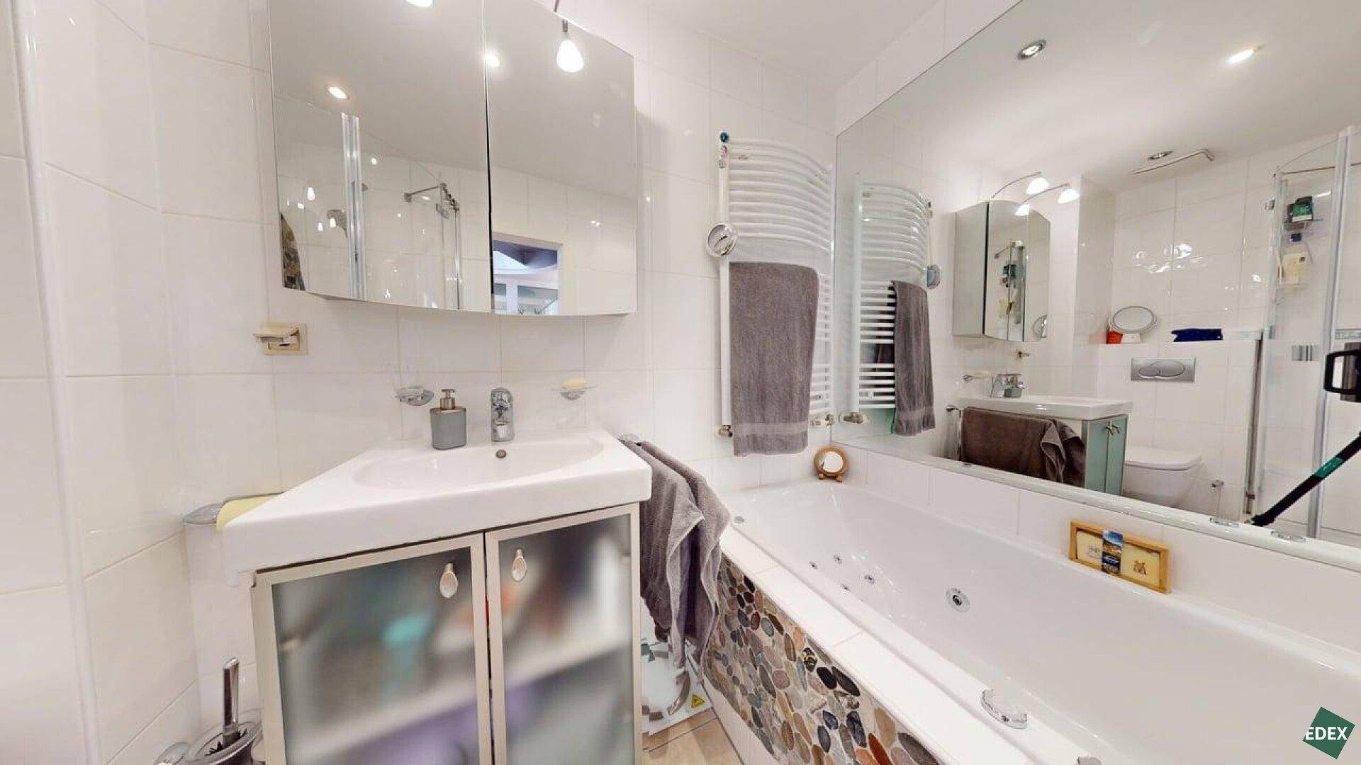 Modernes Badezimmer mit Badewanne, Einzelwaschbecken und beheiztem Handtuchhalter.