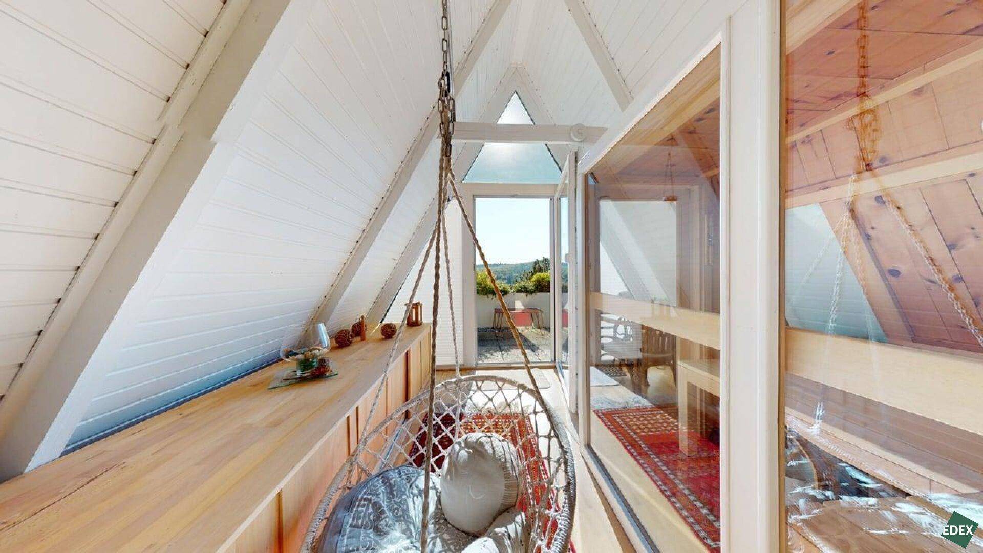 Entspannungsbereich mit Hängesessel, Holzelementen und Blick auf die Dachterrasse.