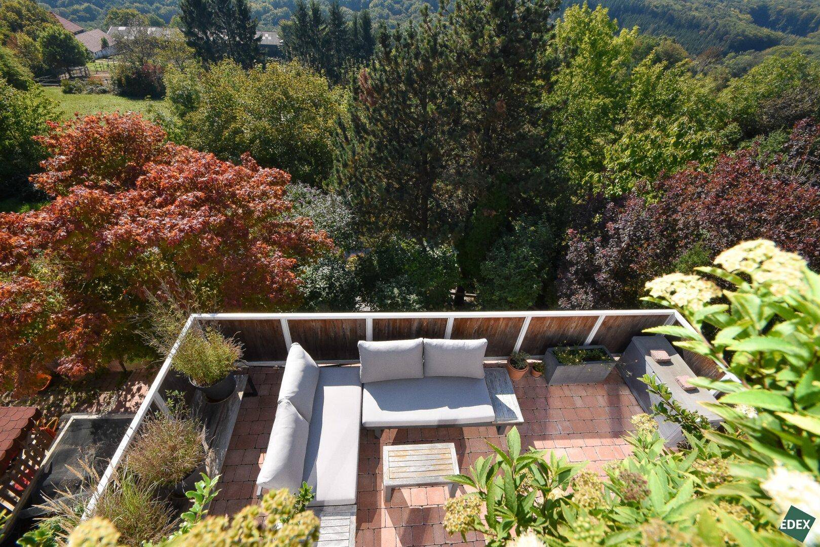 Möblierte Dachterrasse mit bequemen Lounge-Möbeln und weitem Blick ins Grüne.