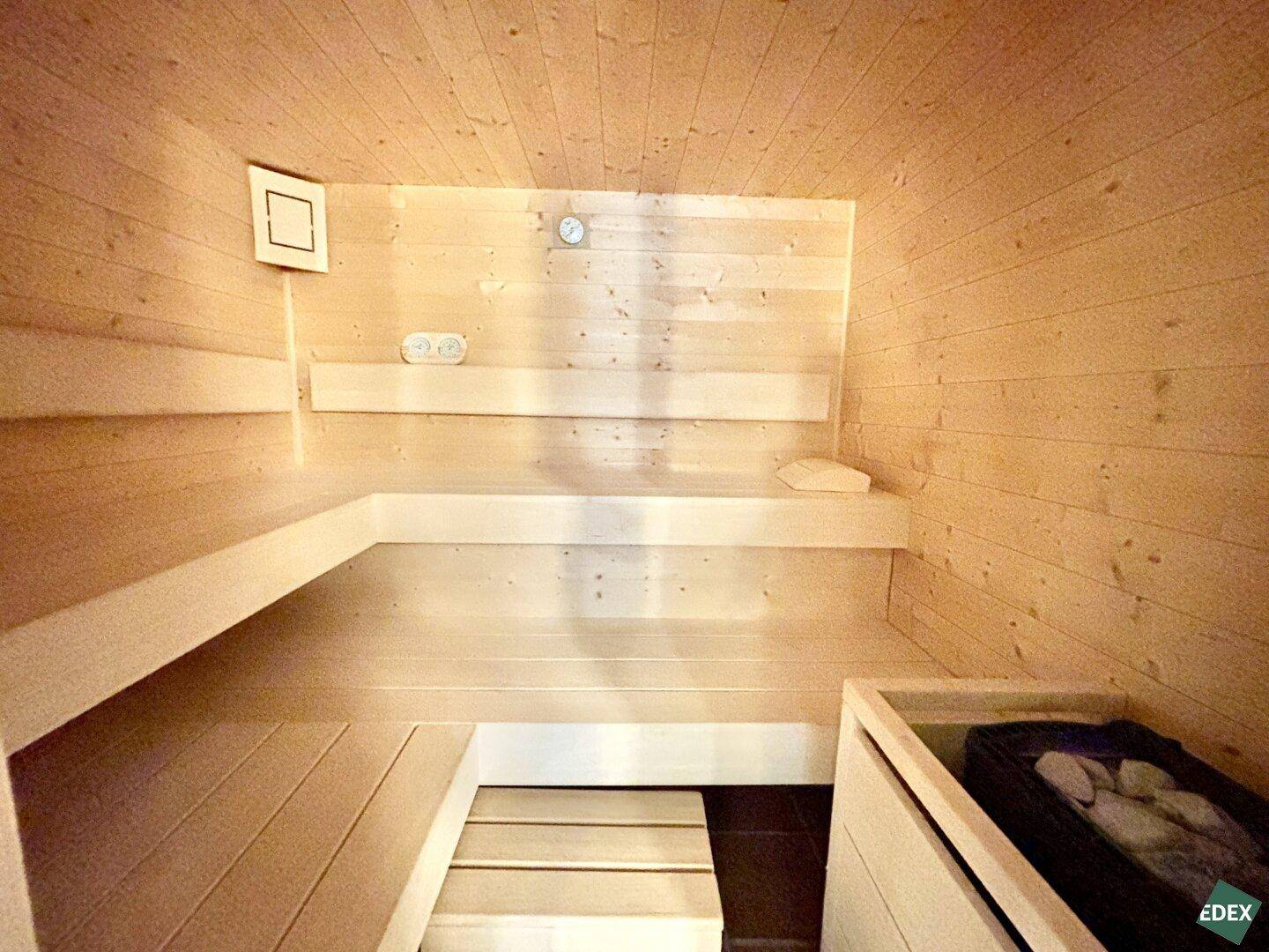 Gemütliche Holzsauna mit mehreren Bänken und traditionellem Saunaofen für Entspannung.