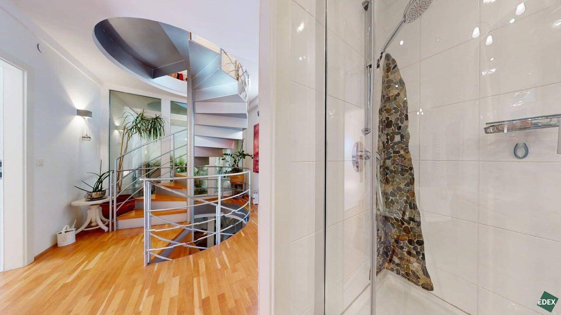 Heller Flur mit moderner Wendeltreppe und Zugang zu einem Badezimmer.