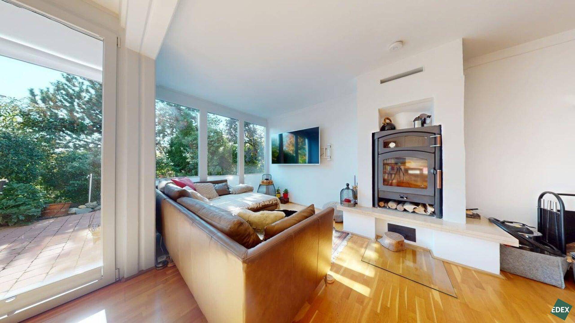 Gemütliches Wohnzimmer mit Kaminofen, Holzboden und Zugang zur Außenterrasse.