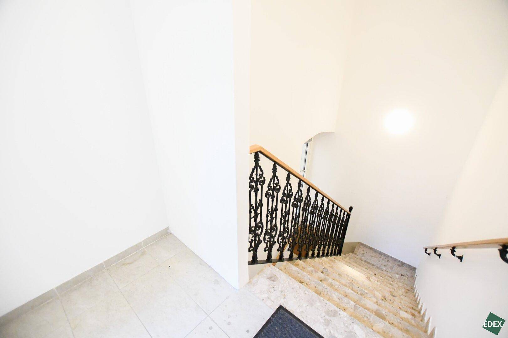 Elegantes Treppenhaus mit Marmorstufen, schmiedeeisernem Geländer und Holzhandlauf.