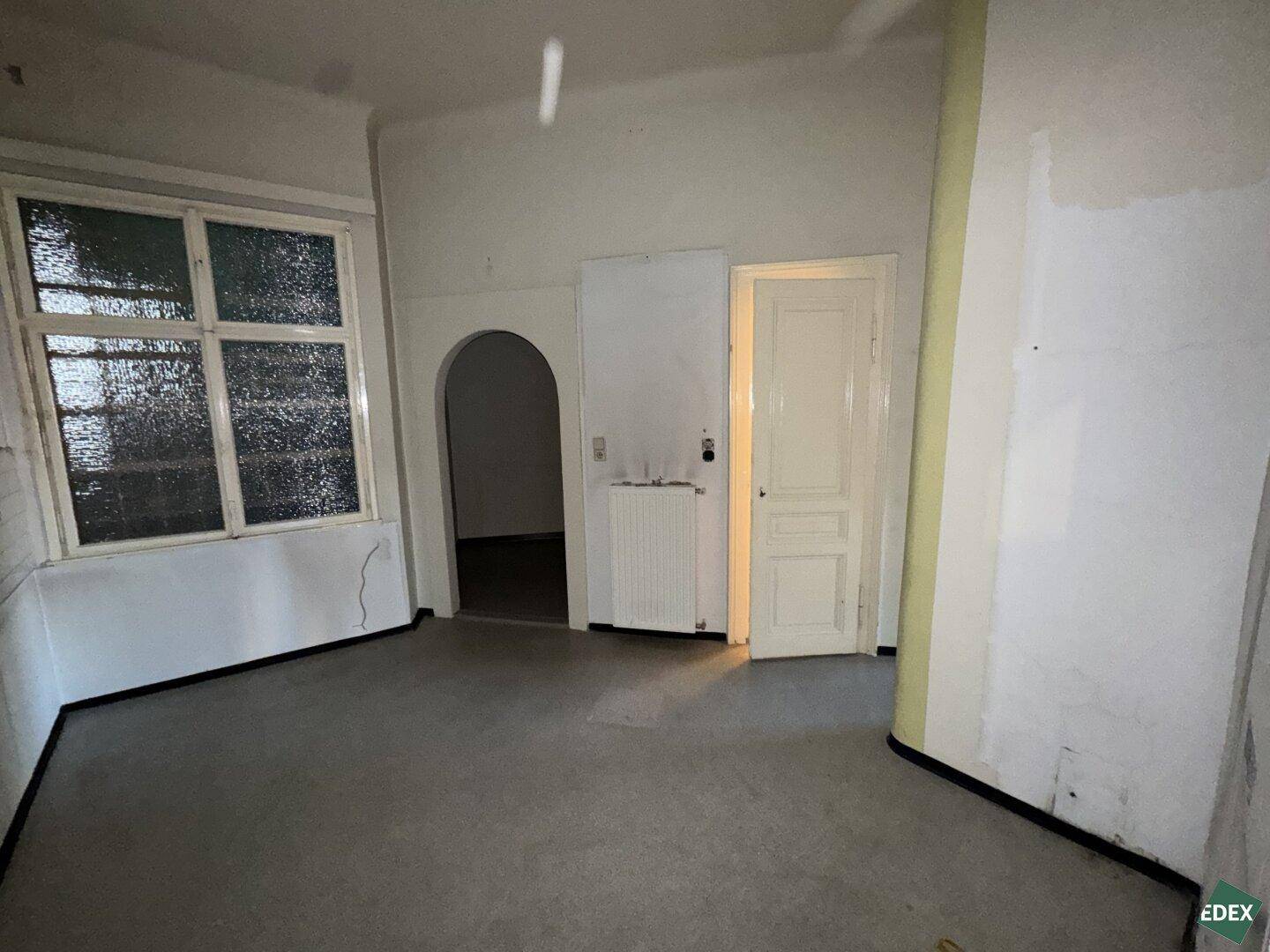 Geräumige Küche mit großem Fenster und Bogenöffnung, bietet viel Gestaltungspotenzial.
