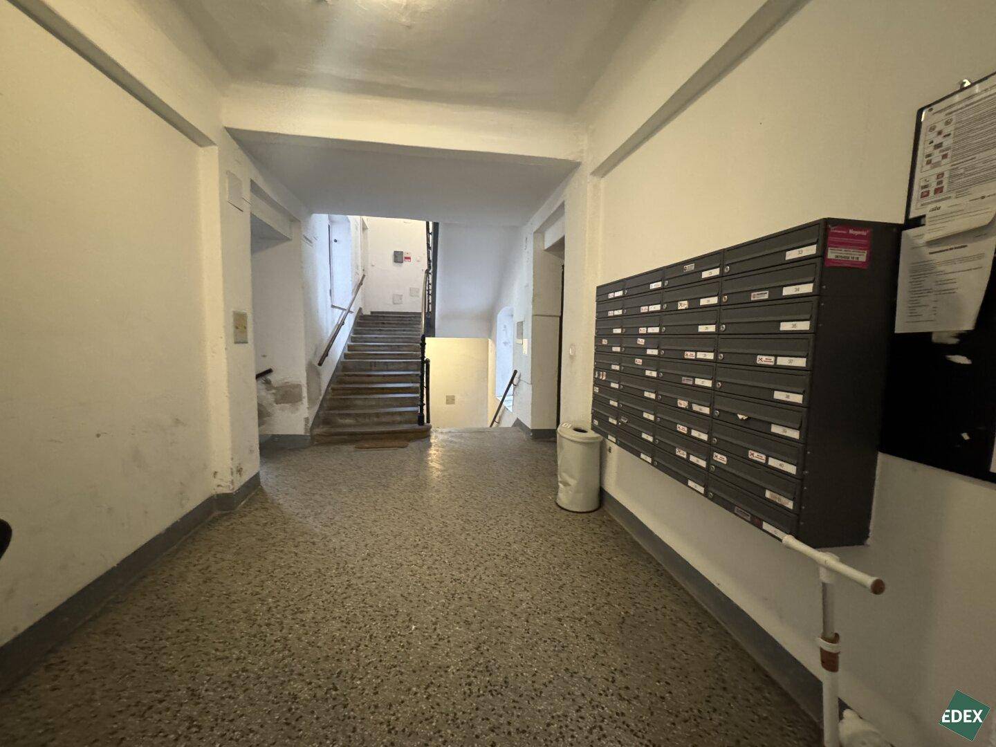 Gemeinschaftlicher Treppenhausbereich eines Altbaus mit Briefkästen und Zugang zur Treppe.