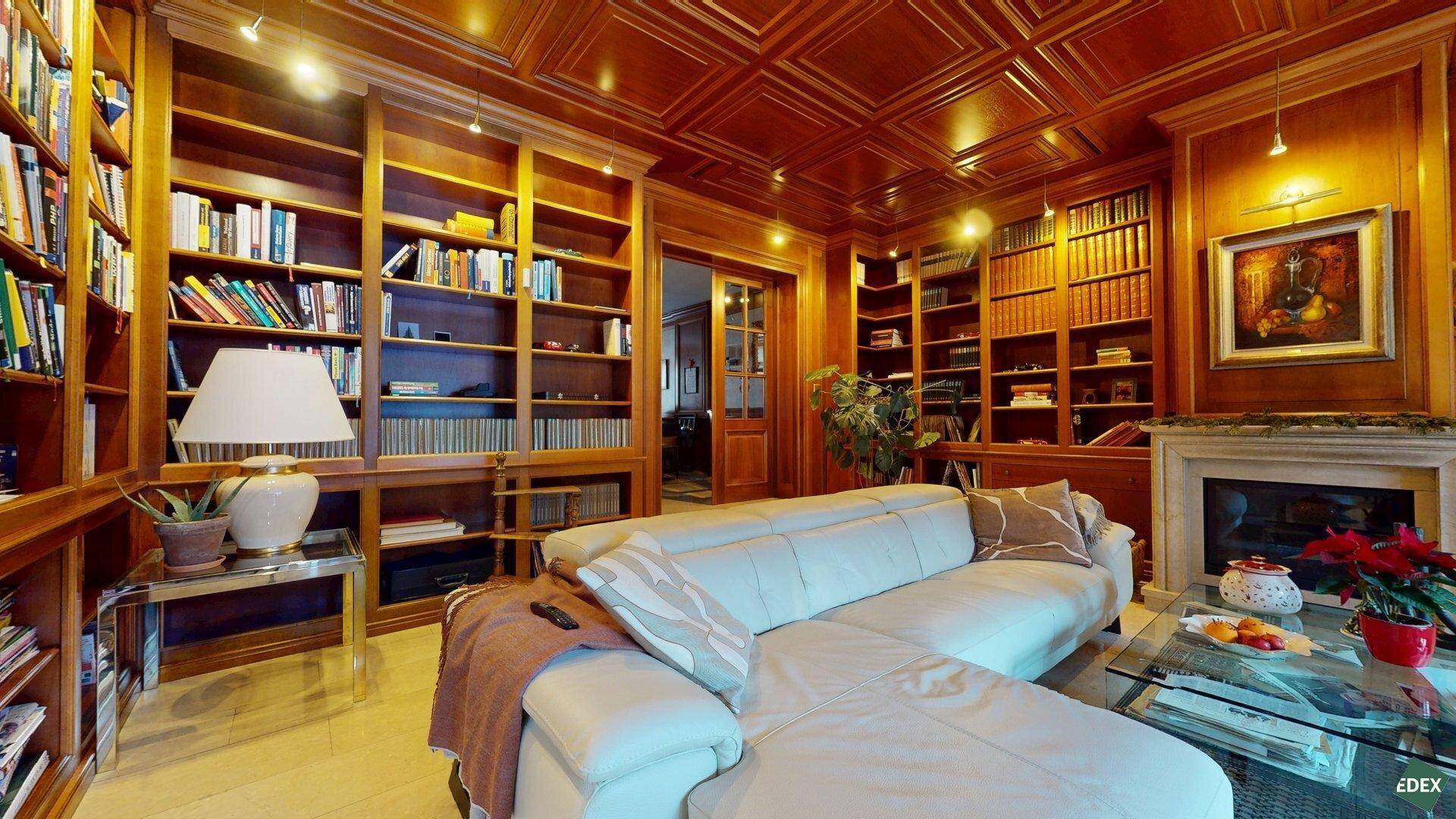 Gemütliche Bibliothek mit bequemer Couch, raumhohen Bücherregalen und klassischer Holzvertäfelung.