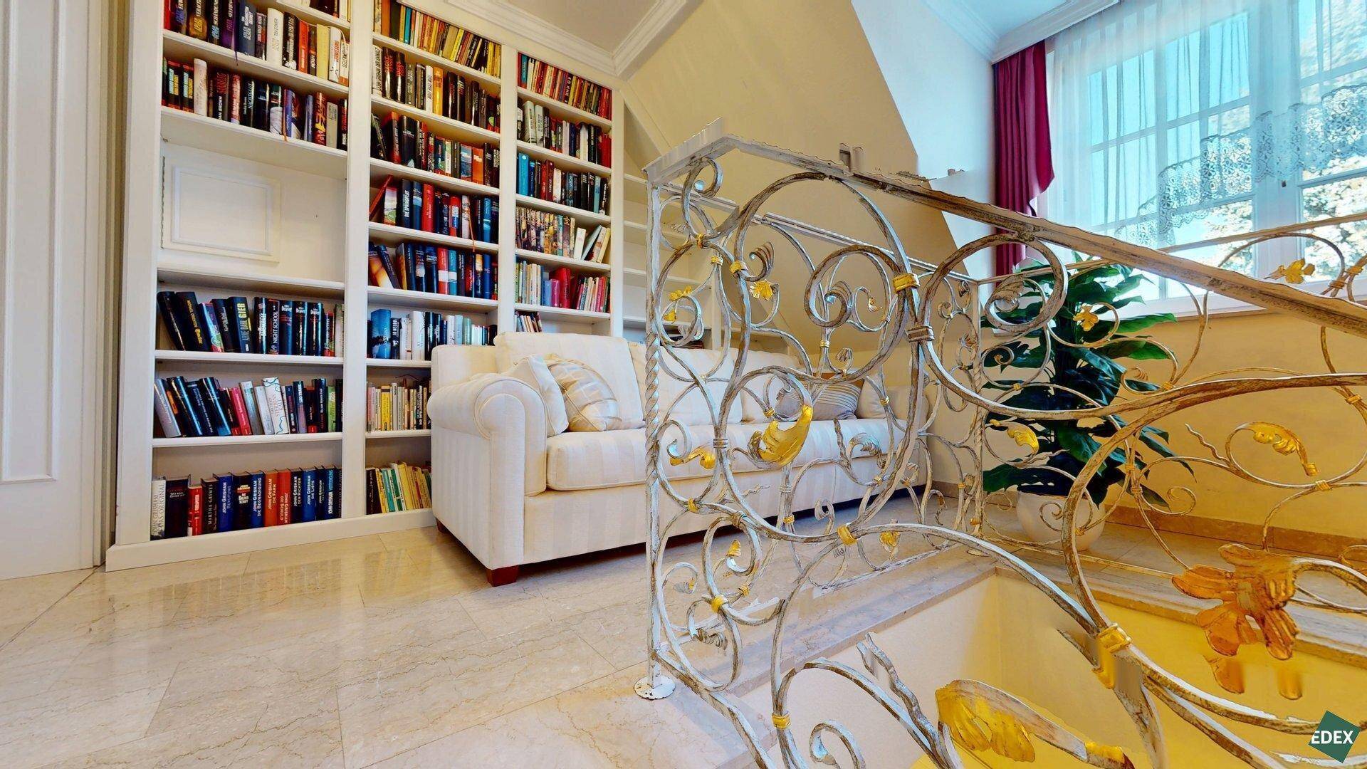 Gemütlicher Lesebereich auf dem Treppenabsatz mit eingebauten Bücherregalen und einem kleinen Sofa.