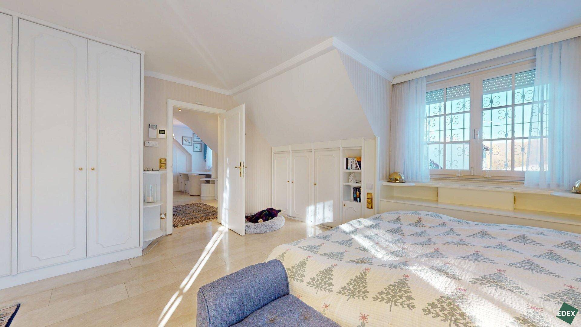 Geräumiges Schlafzimmer mit Einbauschränken, Marmorboden und Blick auf den angrenzenden Bereich.