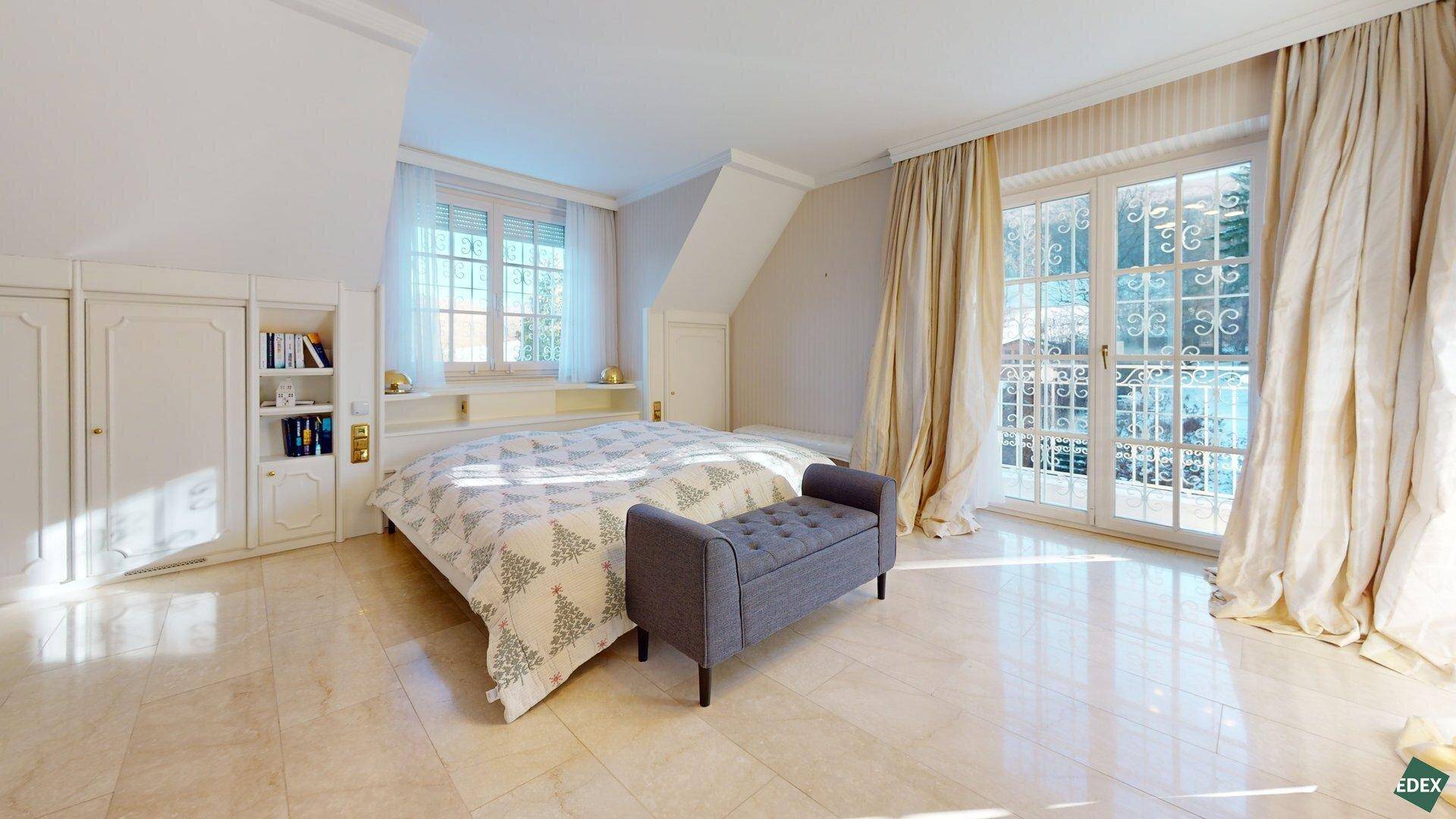 Helles Schlafzimmer mit Marmorboden, Einbauschränken und Zugang zu einem französischen Balkon.