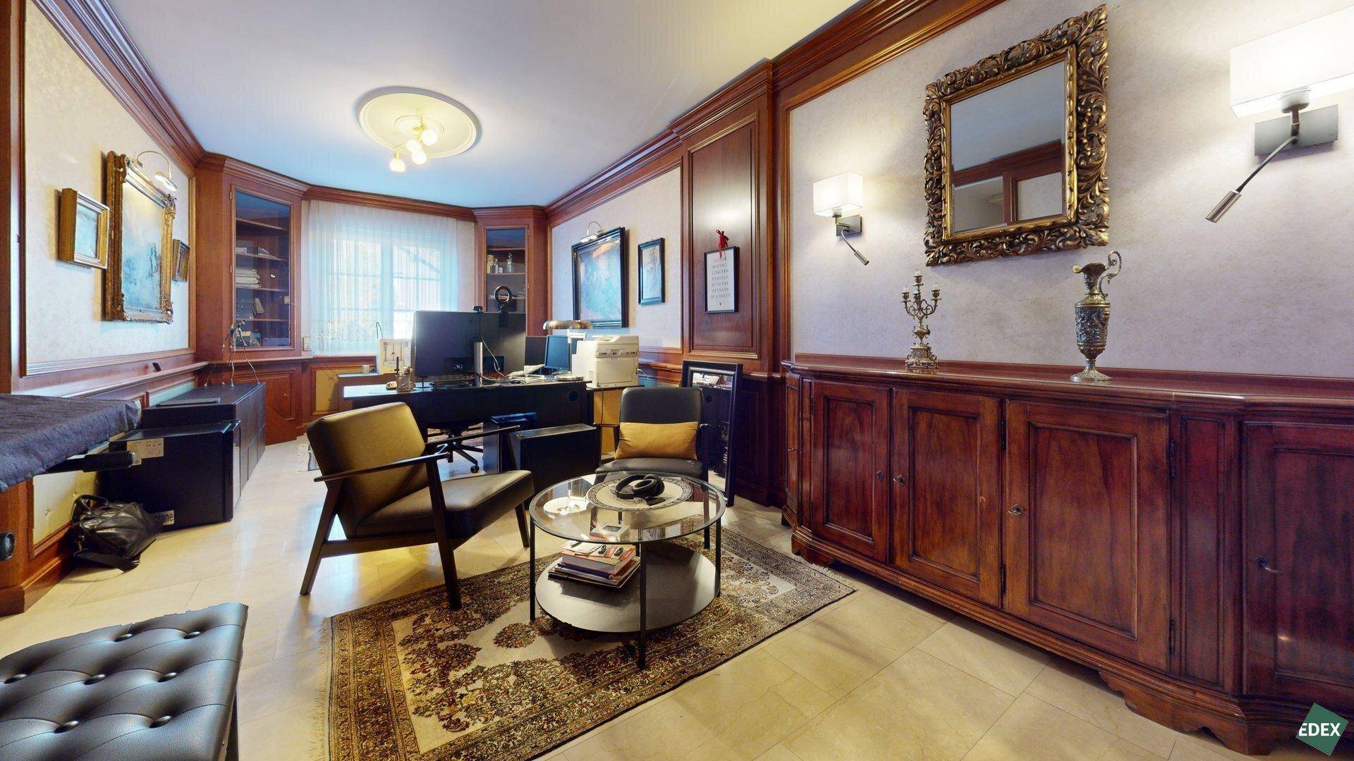 Klassisches Arbeitszimmer mit dunklen Holzvertäfelungen, Schreibtisch und traditionellen Möbeln.