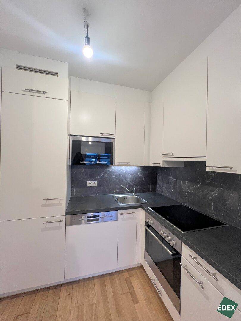 Funktionale Küchenzeile mit integriertem Geschirrspüler, Backofen und Mikrowelle, ideal für kleine Räume.