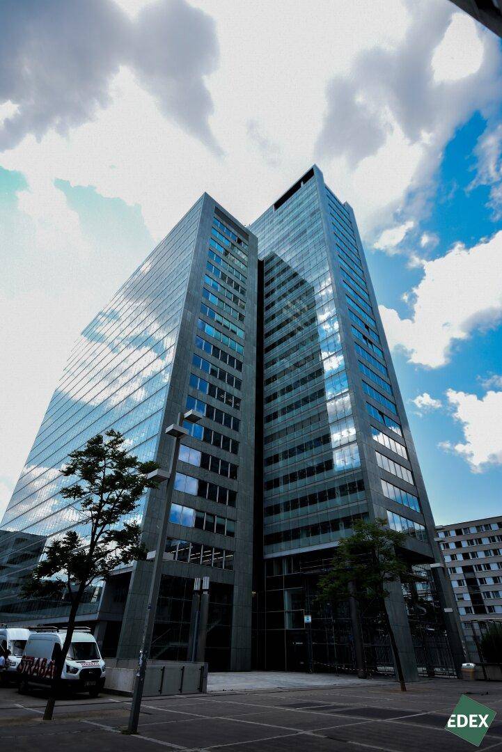 Beeindruckendes modernes Hochhaus mit Glasfassade und klaren Linien unter einem dramatischen Himmel.
