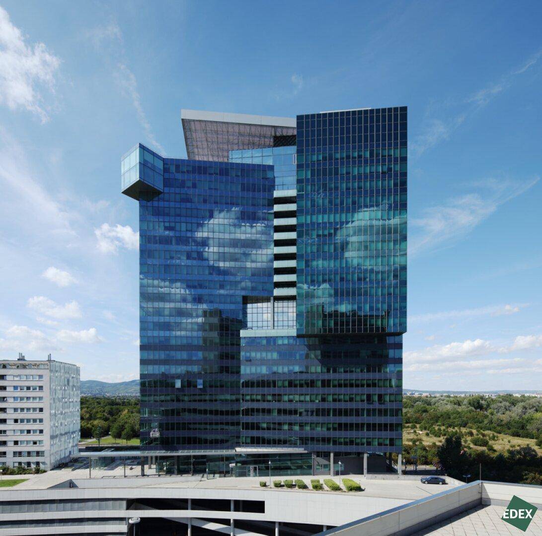 Beeindruckendes modernes Hochhaus mit spiegelnder Glasfassade unter blauem Himmel.