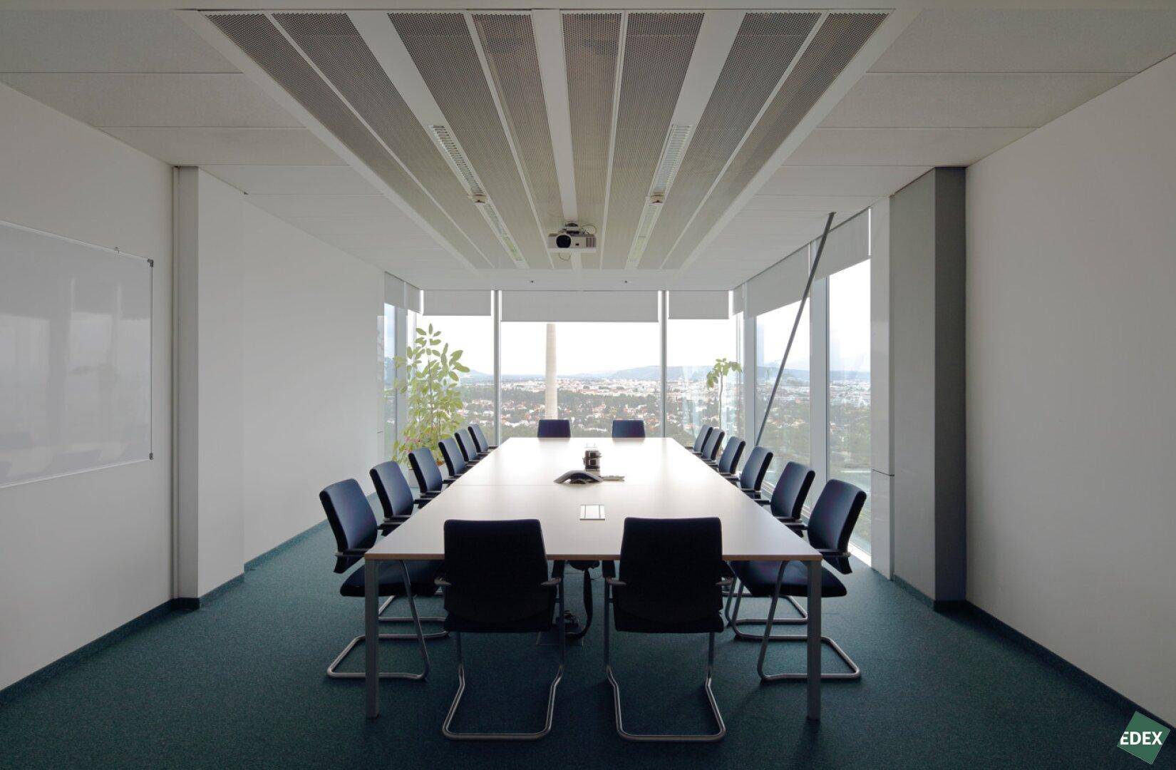 Großer Konferenzraum mit langem Tisch, vielen Stühlen und weitem Ausblick über die Stadt.