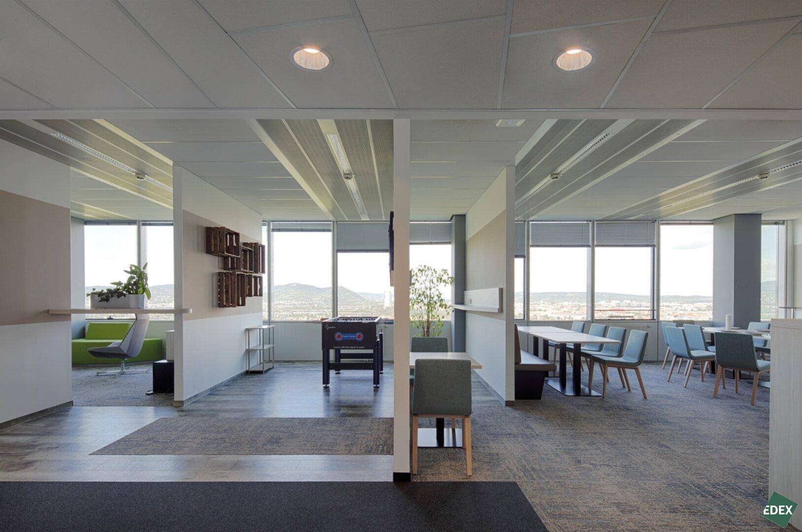 Offener Pausenraum mit verschiedenen Sitzbereichen, Tischfußball und Panoramablick.