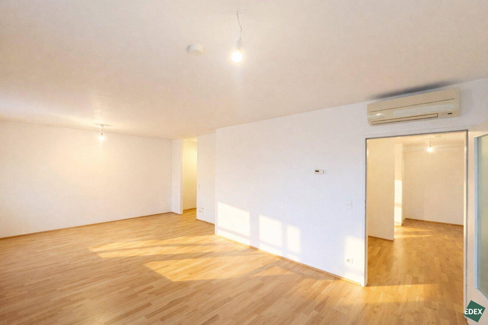Geräumiger, heller Innenraum mit Holzfußboden und Klimaanlage, der vielseitig nutzbar ist.